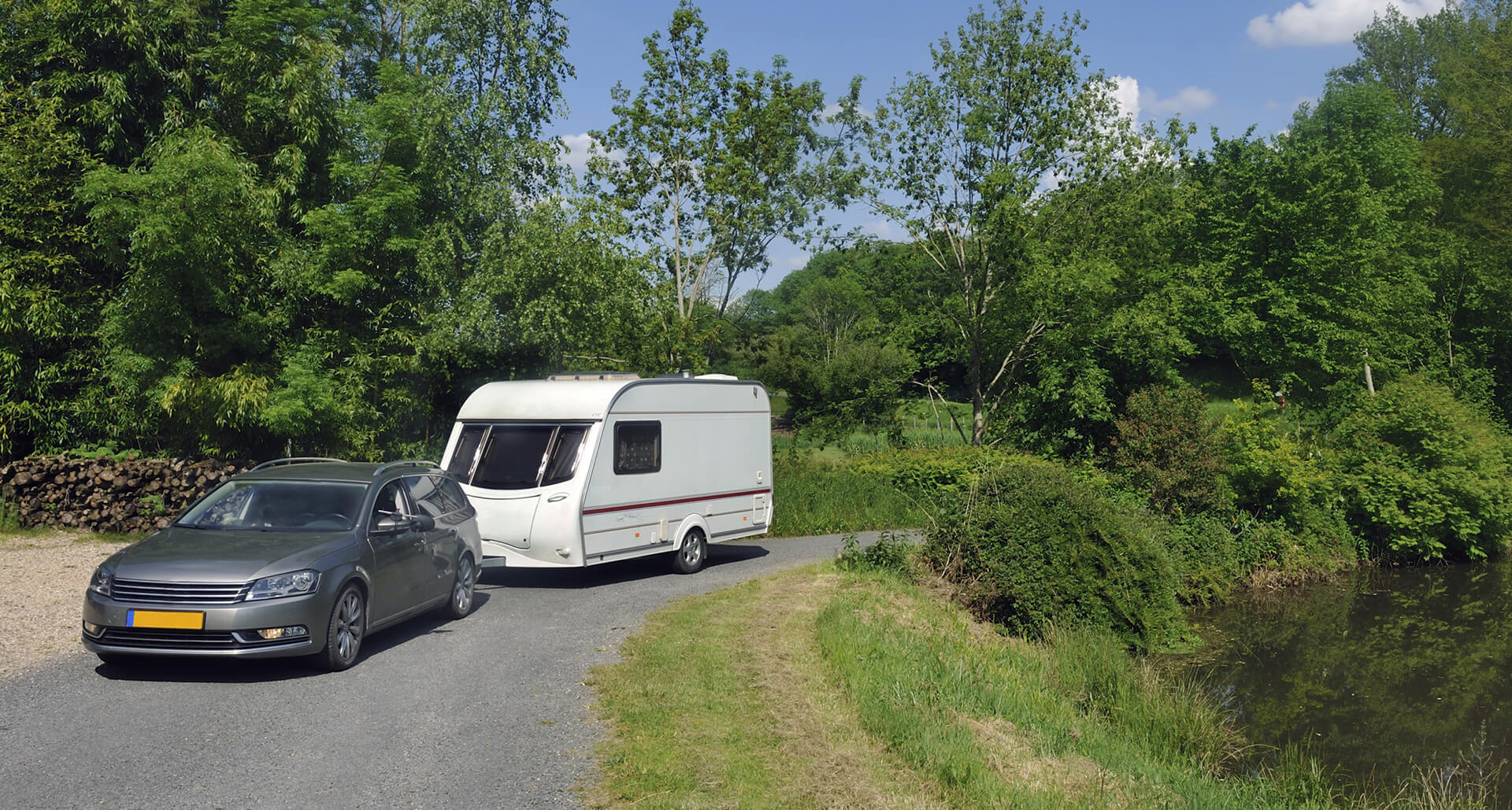 Auto met caravan op landelijke weg, klaar voor schadeherstel of controle na vakantie