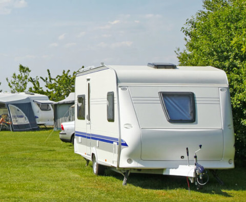 Caravan op zonnige camping na vakantie, mogelijk geschikt voor controle of schadeherstel